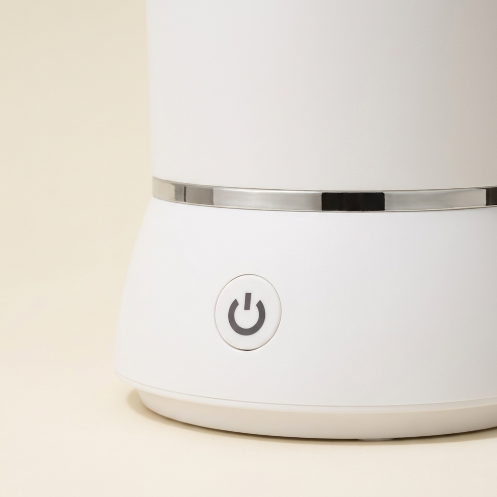 Detail of the white paw cleaner’s front power button and silver band.