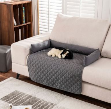 Alfombrilla impermeable para mascotas CloudSleep – perro tumbado en un sofá protegido por la alfombrilla acolchada, con cojines alrededor