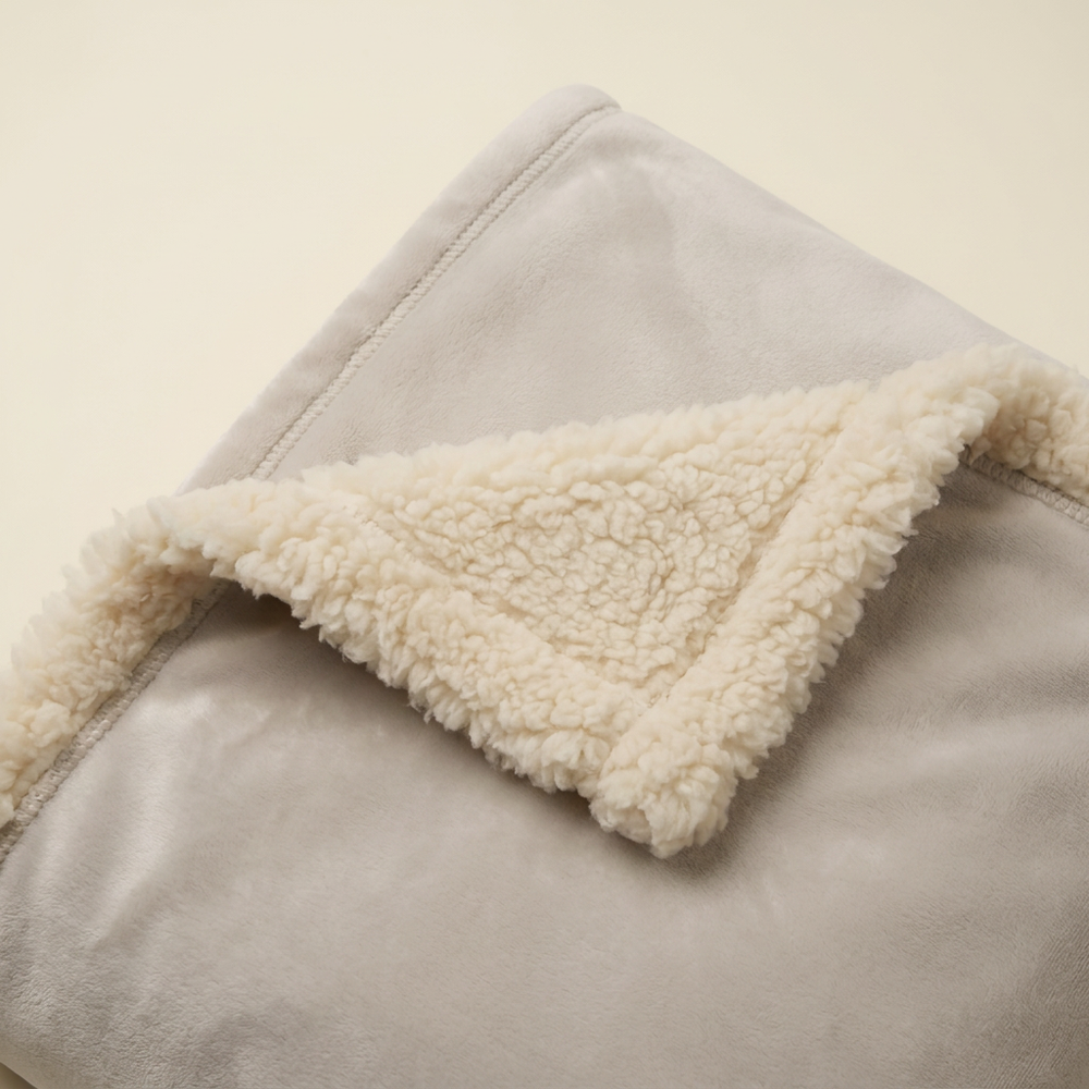 Détail du tissu lisse, de la doublure sherpa crème et de la bordure cousue de la couverture beige.