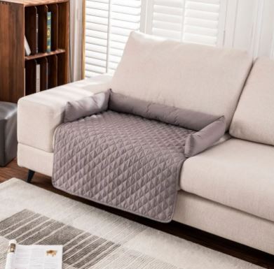 Alfombrilla impermeable para mascotas CloudSleep – alfombrilla acolchada gris y cojines sobre un sofá blanco en un salón