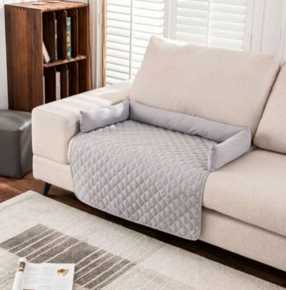 Alfombrilla impermeable para mascotas CloudSleep – alfombrilla acolchada gris claro sobre un sofá blanco en un salón
