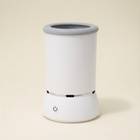White paw cleaner cup with a grey opening, silver band and front power button.
