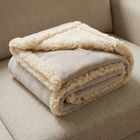Couverture apaisante beige pliée sur un canapé de couleur neutre.