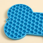 Primer plano de las celdas de panal, el borde elevado y el orificio para colgar de la alfombra azul para lamer.