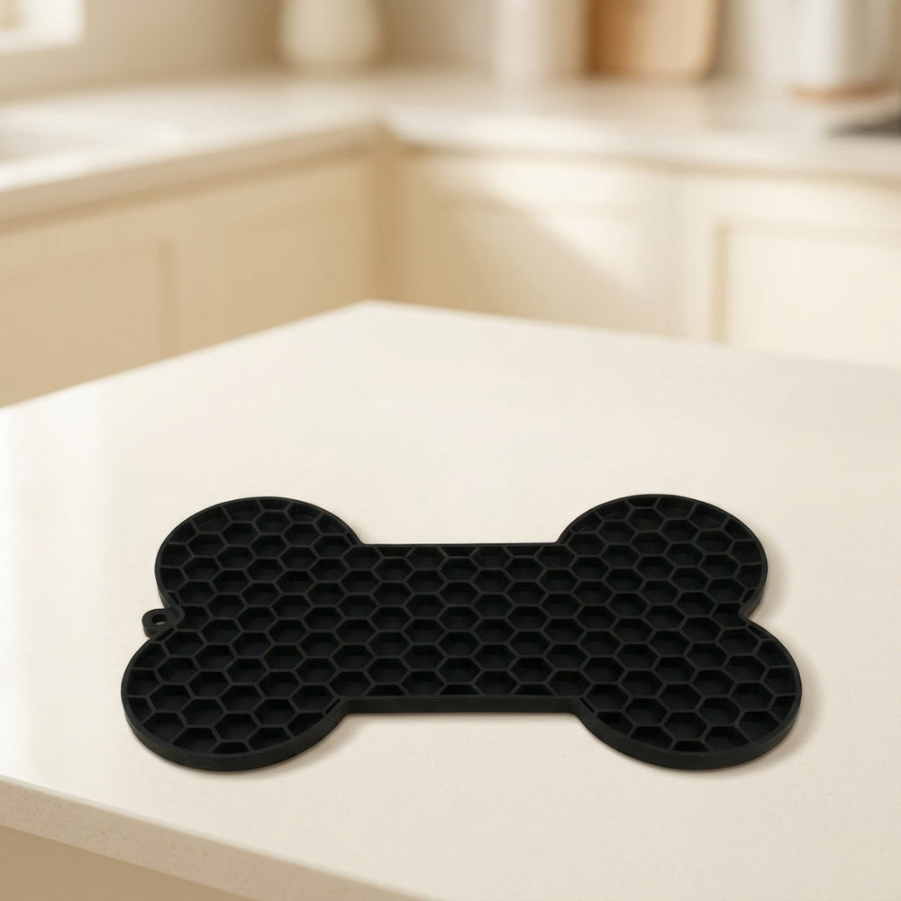 Alfombra negra para lamer en forma de hueso sobre una encimera de cocina clara.