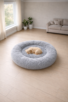 CloudSleep Anti-Anxiety Bed -- dog resting in round light grey bed in living room with sofa and plants